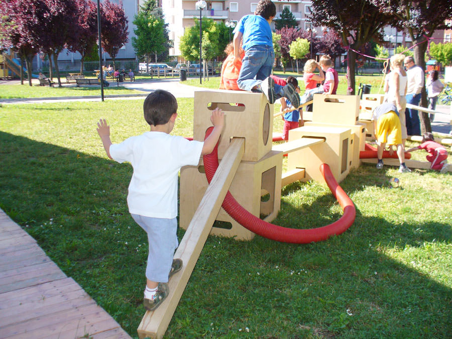 Kinder klettern auf der Bewegungsbaustelle im Freien auf einer Wiese herum.